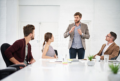 Buy stock photo Shot of a businessman giving a presentation to colleagues sitting at a table in a modern office