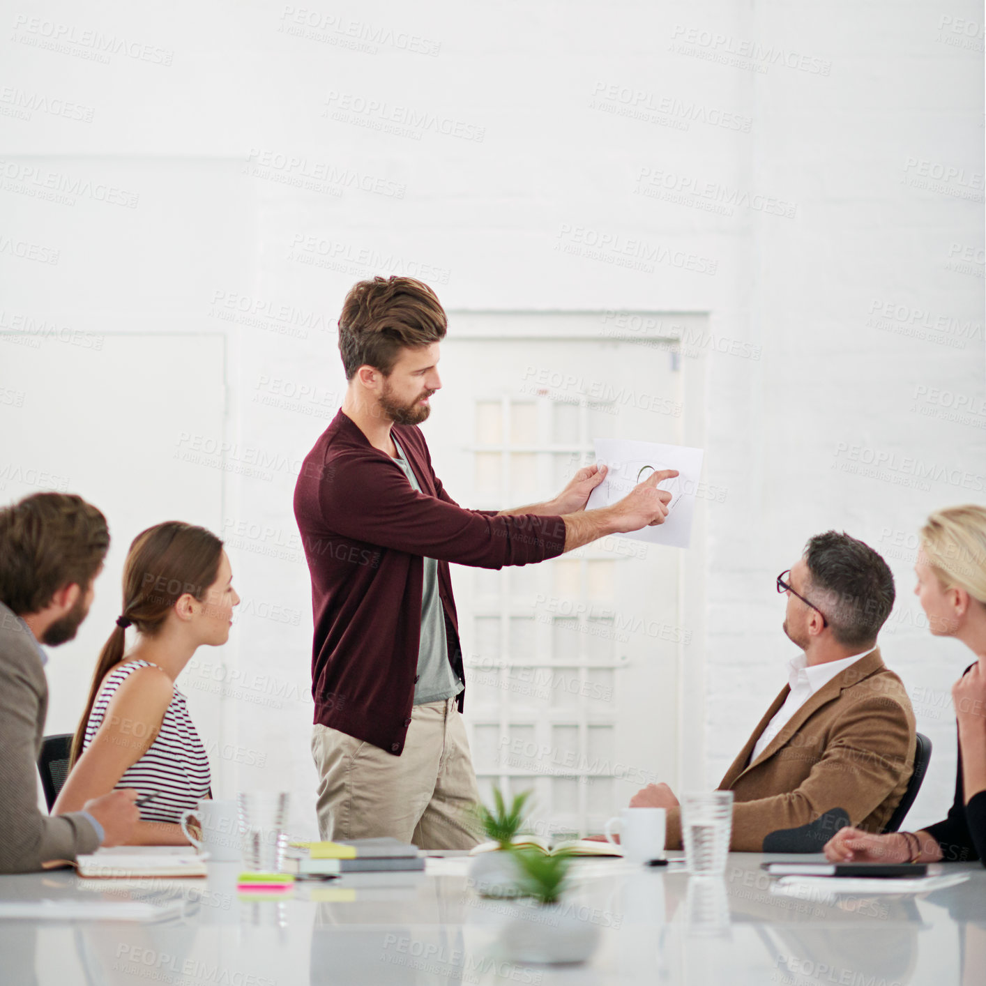 Buy stock photo Shot of a businessman giving a presentation to colleagues sitting at a table in a modern office