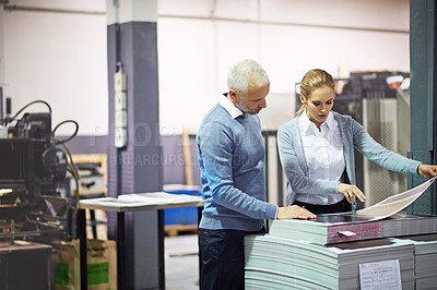 Buy stock photo Shot of two managers looking over samples while standing inside a printing and packaging plant. The commercial designs displayed represent a simulation of a real product and have been changed or altered enough by our team of retouching and design specialists so that they don't have any copyright infringements