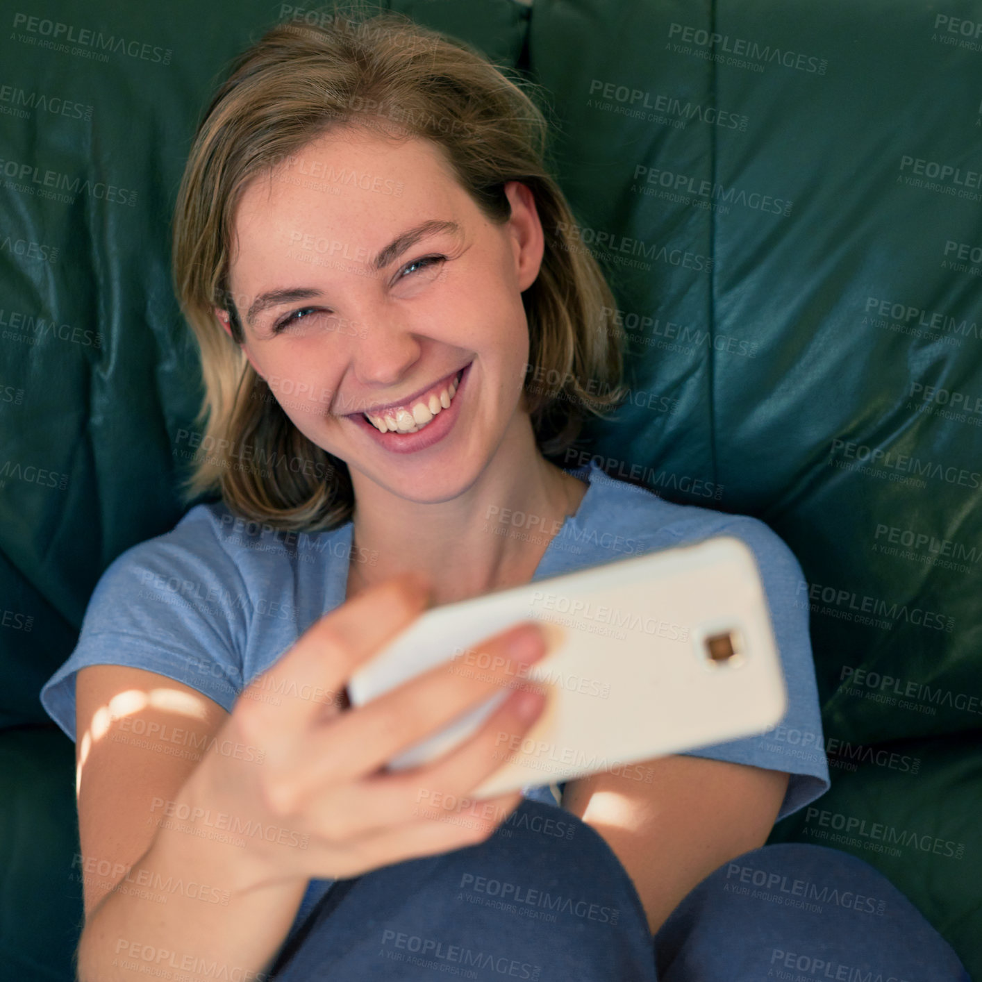 Buy stock photo Shot of a happy young woman taking a selfie with her smatphone at home