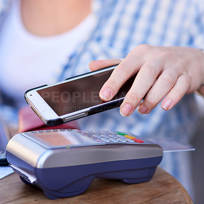 Buy stock photo Shot of an unidentifiable woman making a mobile payment with her smartphone and a card machine at a cafe