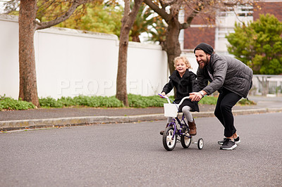 Buy stock photo Shot of a father teaching his little daughter how to ride a bicycle