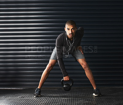 Buy stock photo Shot of an athletic young man working out with a kettlebell in the gym