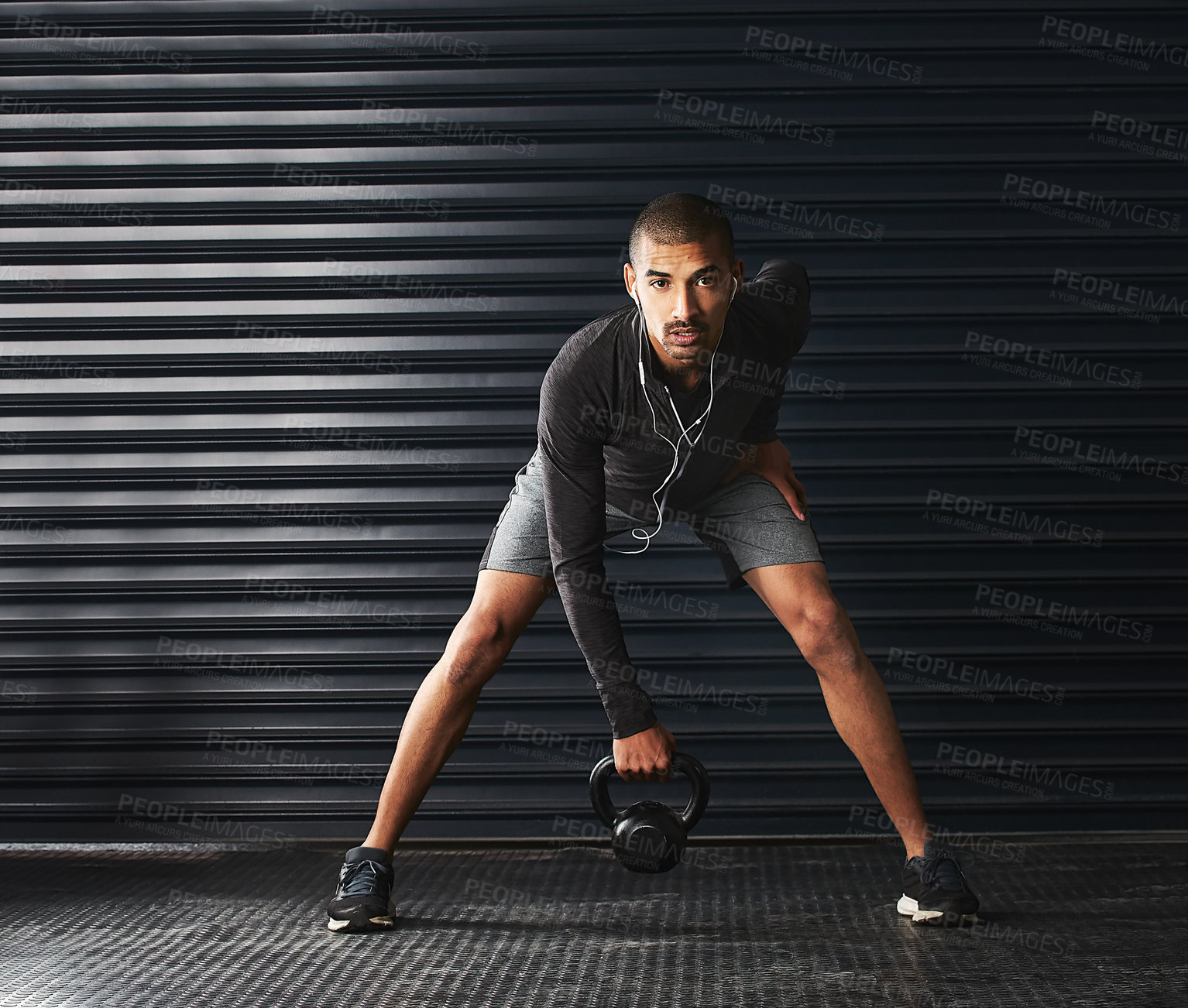 Buy stock photo Shot of an athletic young man working out with a kettlebell in the gym