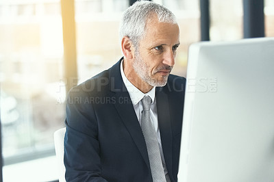 Buy stock photo Shot of a focused mature businessman working on his computer in an office