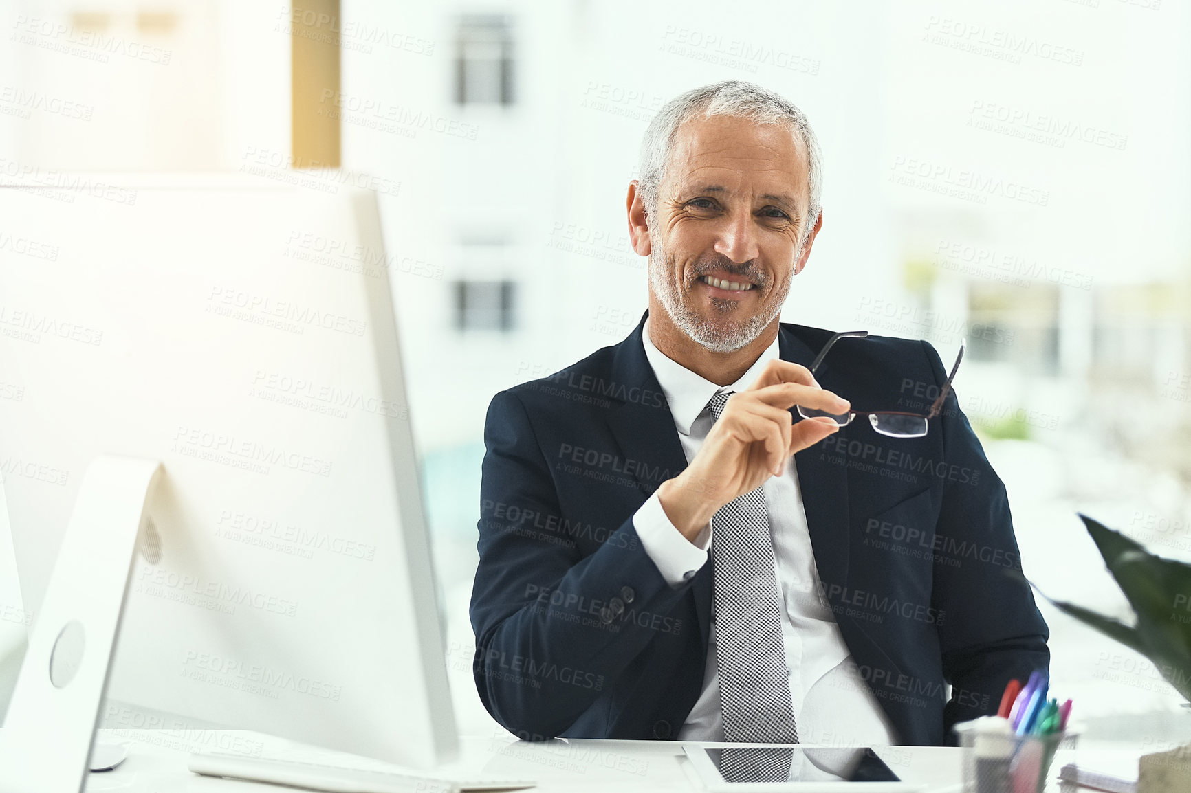 Buy stock photo Portrait of a smiling mature businessman sitting at his desk in an office