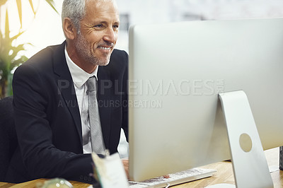 Buy stock photo Shot of a smiling mature businessman working on his computer in an office