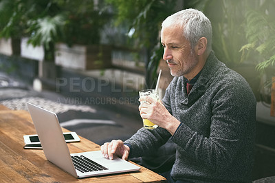 Buy stock photo Shot of a mature businessman using his laptop in a cafe