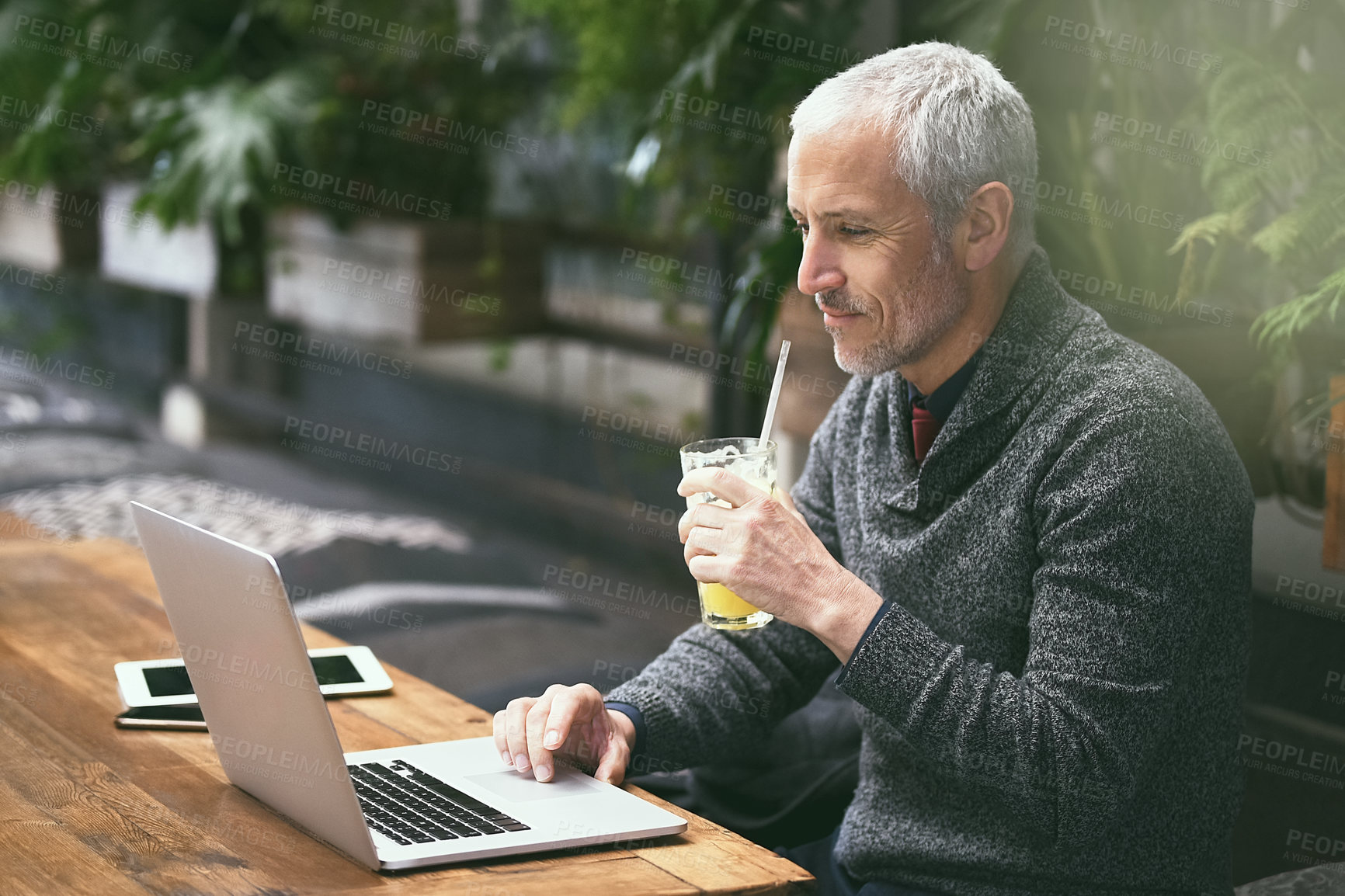 Buy stock photo Shot of a mature businessman using his laptop in a cafe