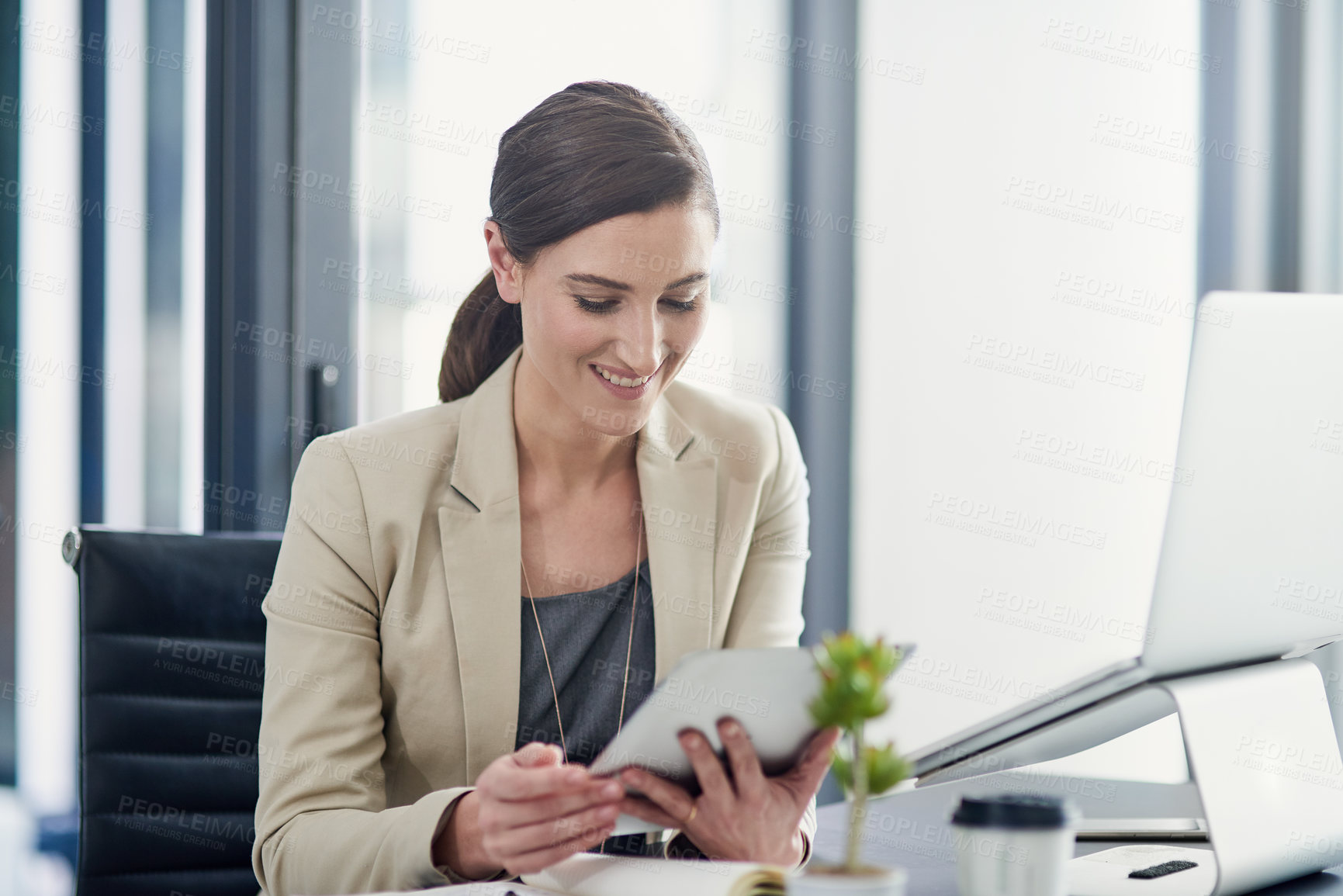 Buy stock photo Shot of a professional businesswoman using a digital tablet at her office desk