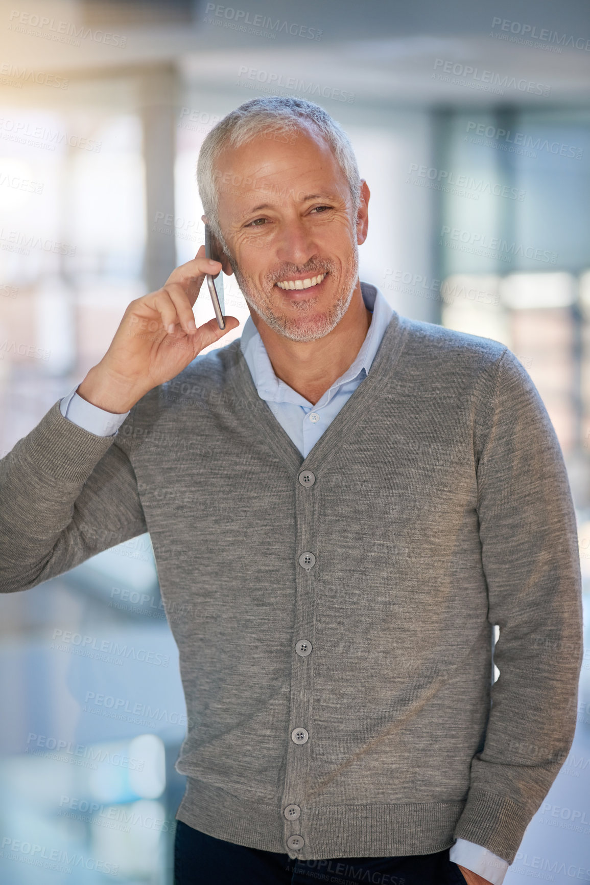 Buy stock photo Shot of a mature businessman making a phonecall while walking in his office