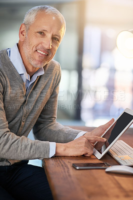 Buy stock photo Portrait of a mature businessman using his digital tablet in the office