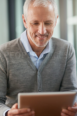 Buy stock photo Shot of a mature businessman using his digital tablet in the office