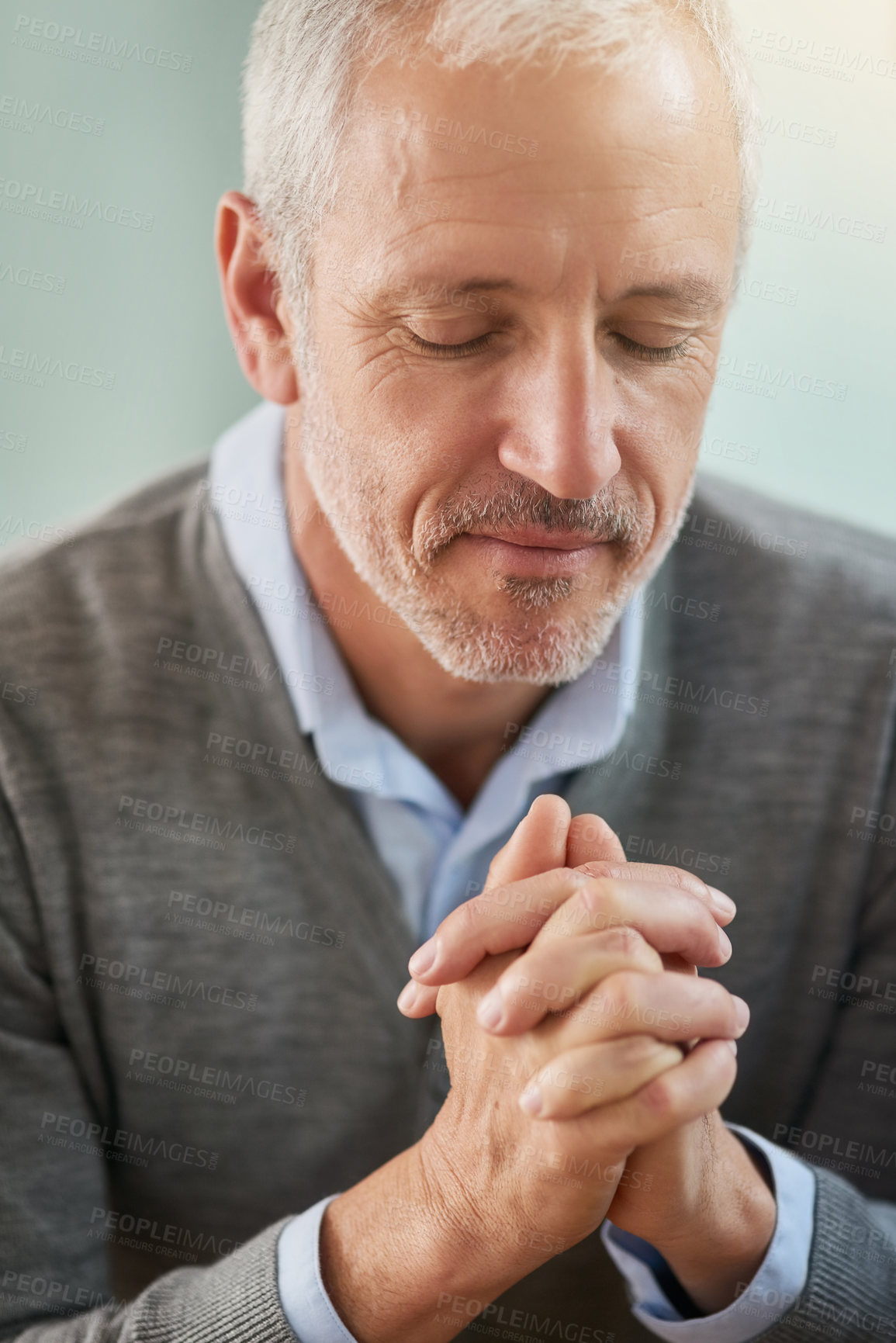 Buy stock photo Shot of a mature businessman praying while sitting in his office