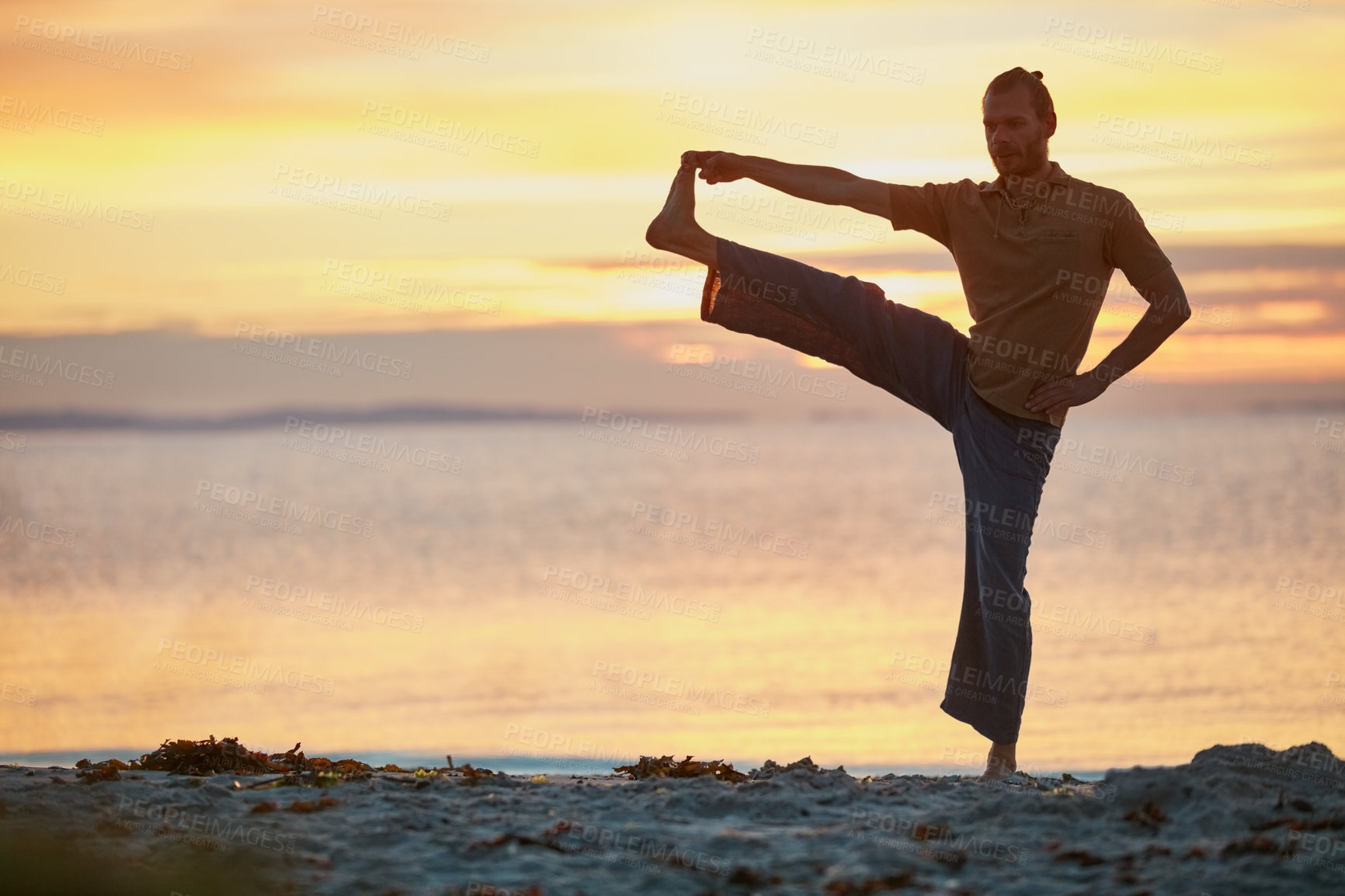 Buy stock photo Shot of a man practicing yoga at the beach during sunset