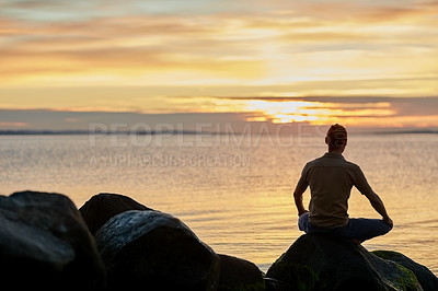 Buy stock photo Shot of a man sitting in the lotus position during his yoga routine at the beach