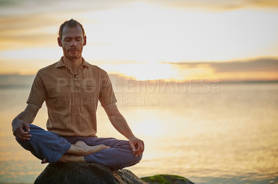 Buy stock photo Shot of a man sitting in the lotus position during his yoga routine at the beach