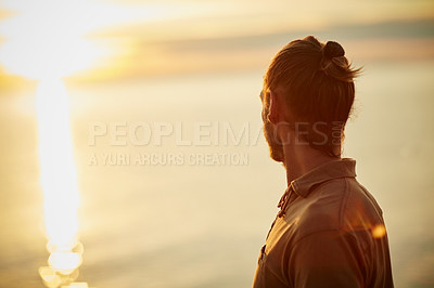 Buy stock photo Shot of a man watching the sun go down at the beach