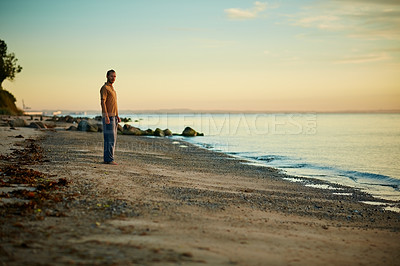 Buy stock photo Shot of a man standing at the water’s edge of a beach