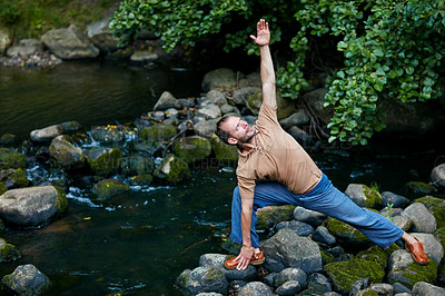 Buy stock photo Shot of a handsome man doing yoga stretches outdoors