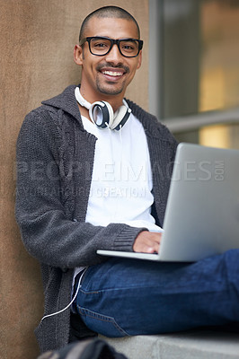 Buy stock photo Portrait of a college student using his laptop while sitting outside at campus