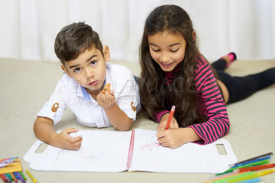 Buy stock photo Shot of a cute little boy and his sister colouring in together at home