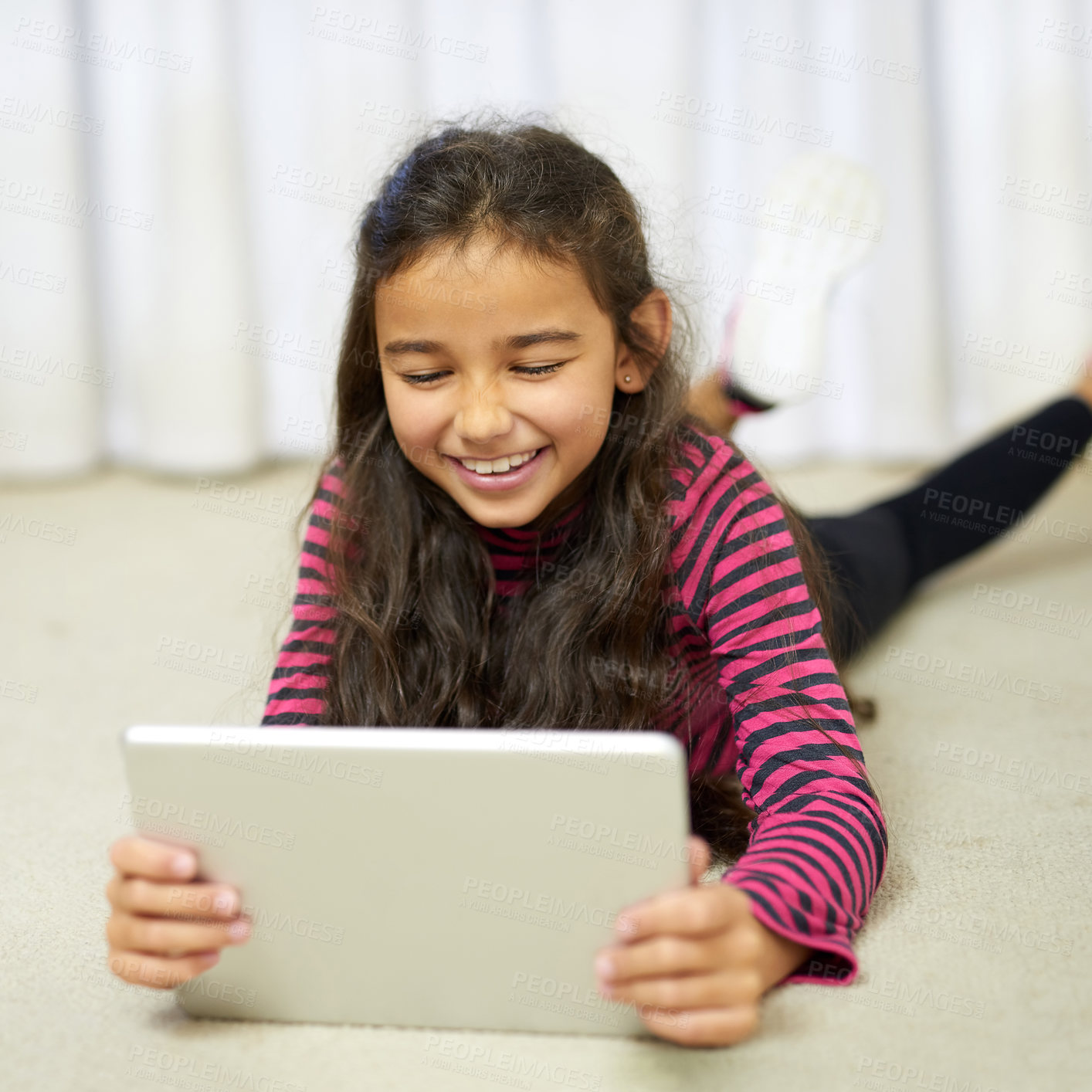 Buy stock photo Shot of a cute little girl using her tablet while lying on the floor at home