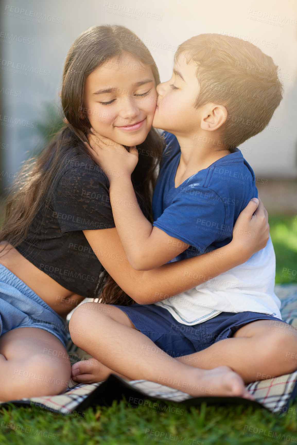 Buy stock photo Shot of a cute little boy giving his sister a kiss while they sit outside