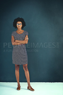 Buy stock photo Portrait of a confident young businesswoman standing with her arms folded in the studio