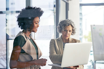 Buy stock photo Shot of two colleagues discussing something on a laptop