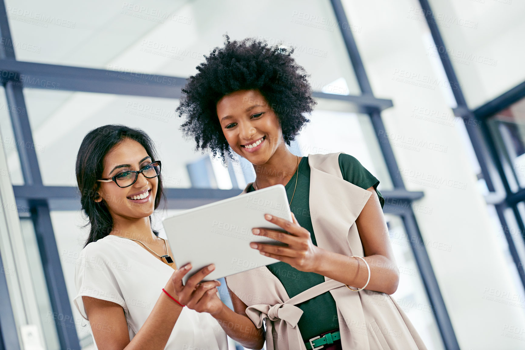 Buy stock photo Shot of two colleagues discussing something on a digital tablet