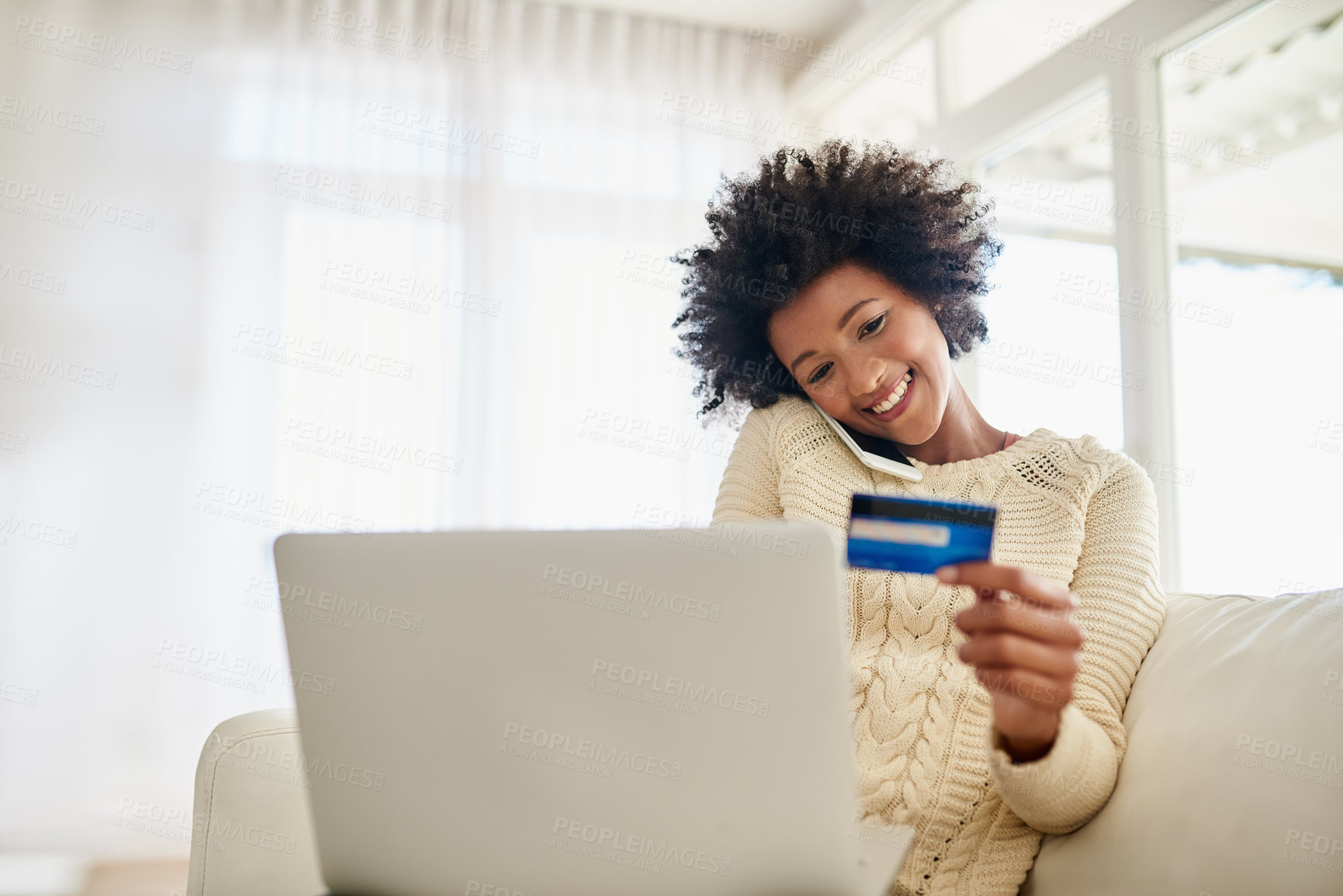 Buy stock photo Shot of an attractive young woman shopping online using her laptop while sitting on the sofa at home
