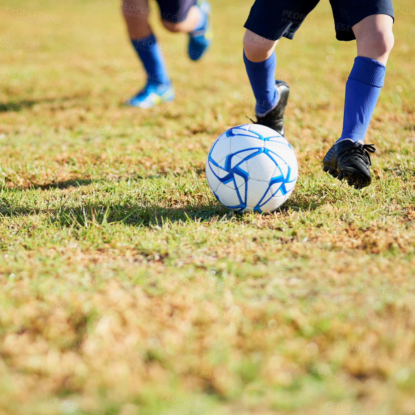 Buy stock photo Shot of two unidentifiable children playing soccer outside on a sunny day