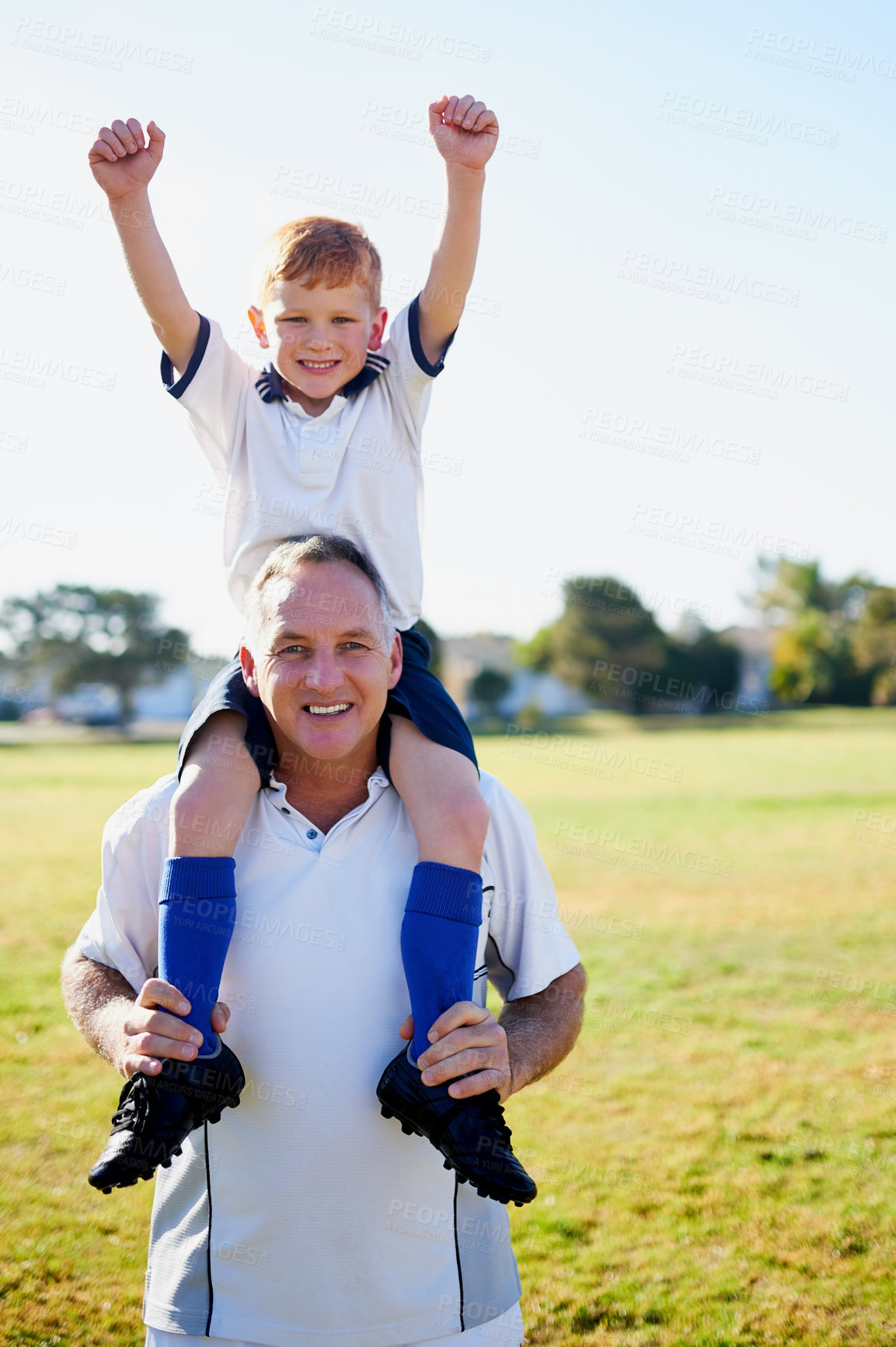 Buy stock photo Portrait of a father carrying his young son on his shoulders after a soccer game