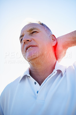Buy stock photo Shot of a man rubbing his sore neck while standing outside