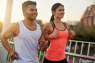 Buy stock photo Couple, fitness and smile running outdoor for exercise, workout or cardio routine together on bridge. Happy, man and woman training or fast walking on road for strength, wellness and healthy bonding