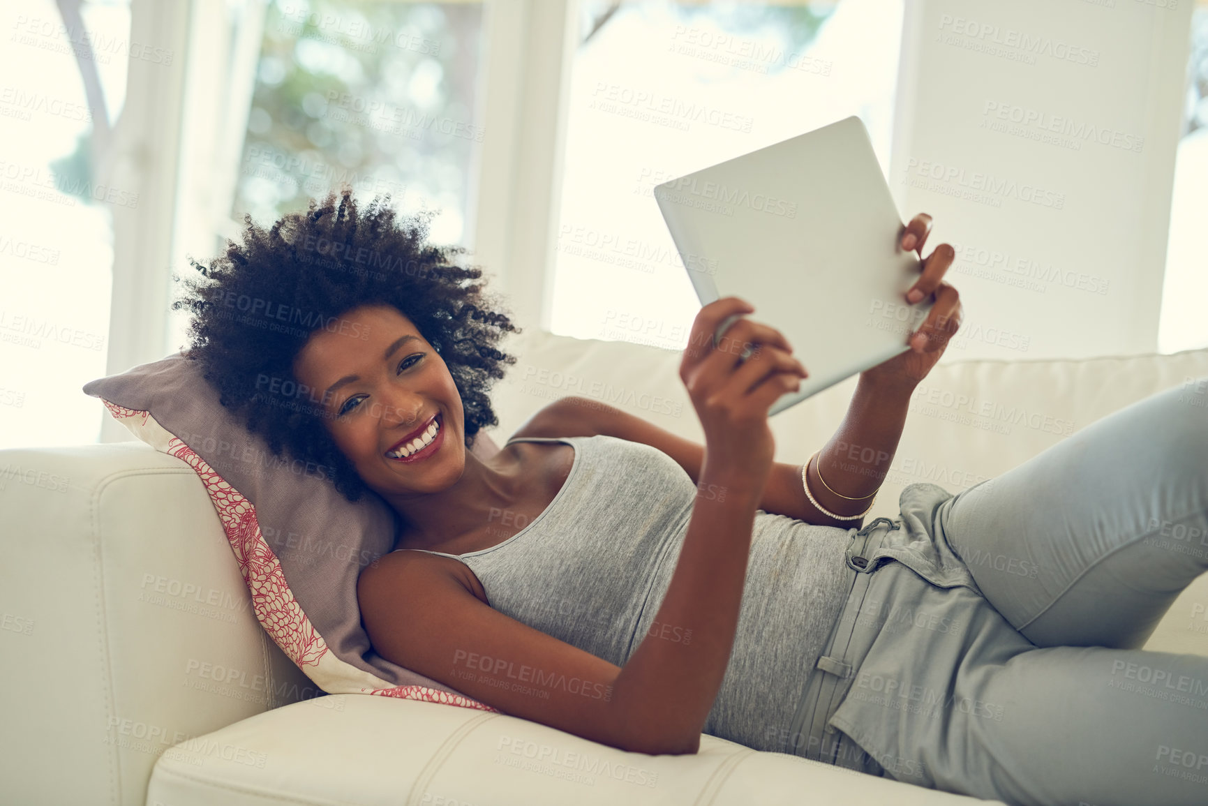 Buy stock photo Portrait of a young woman using her digital tablet while relaxing at home