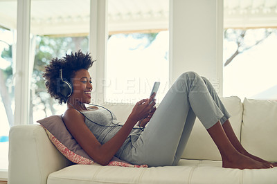 Buy stock photo Shot of a young woman listening to music with headphones while relaxing at home