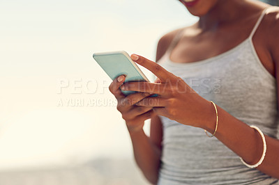 Buy stock photo Cropped shot of a young woman texting on her cellphone