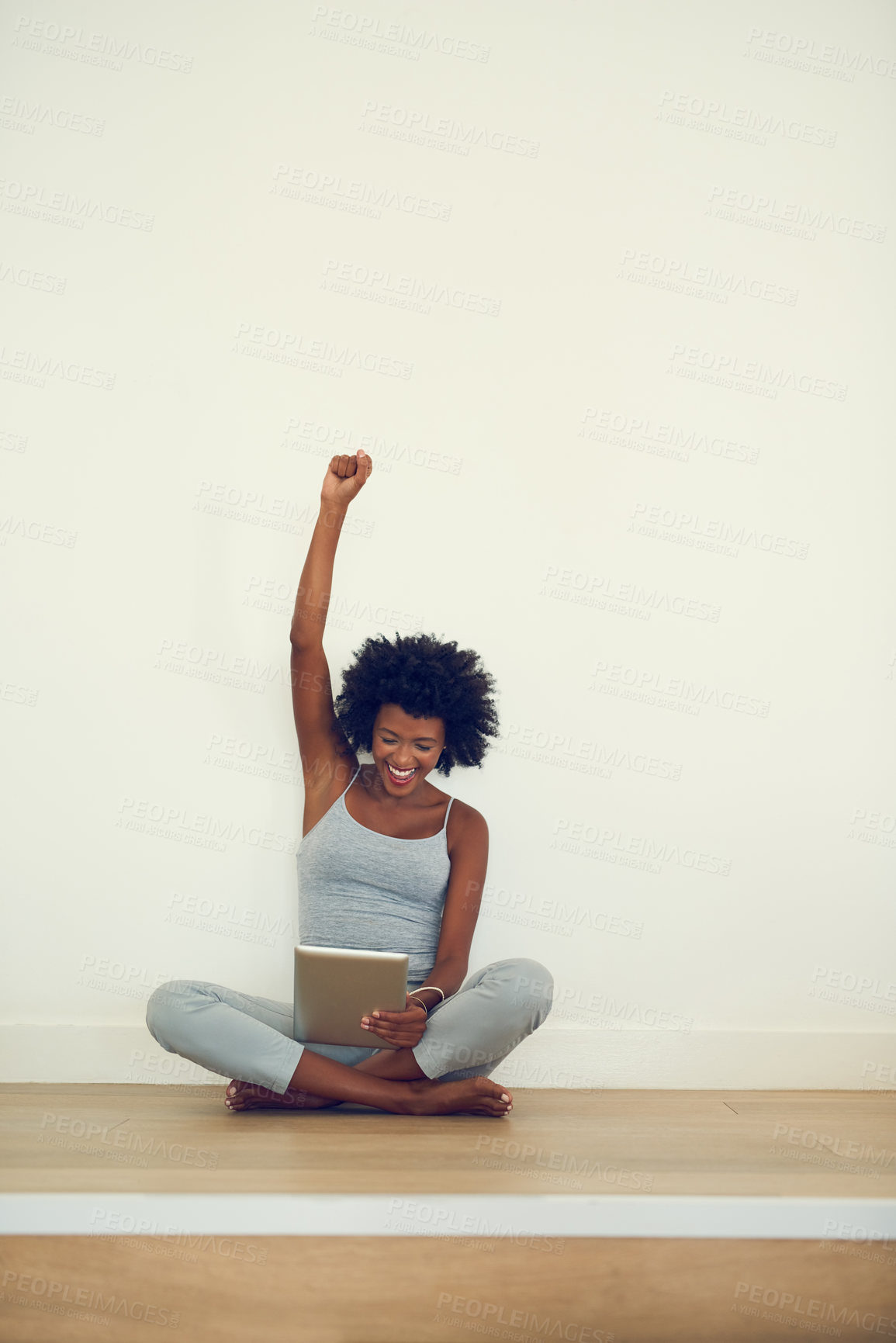 Buy stock photo Shot of a young woman doing a fist pump while using her digital tablet at home