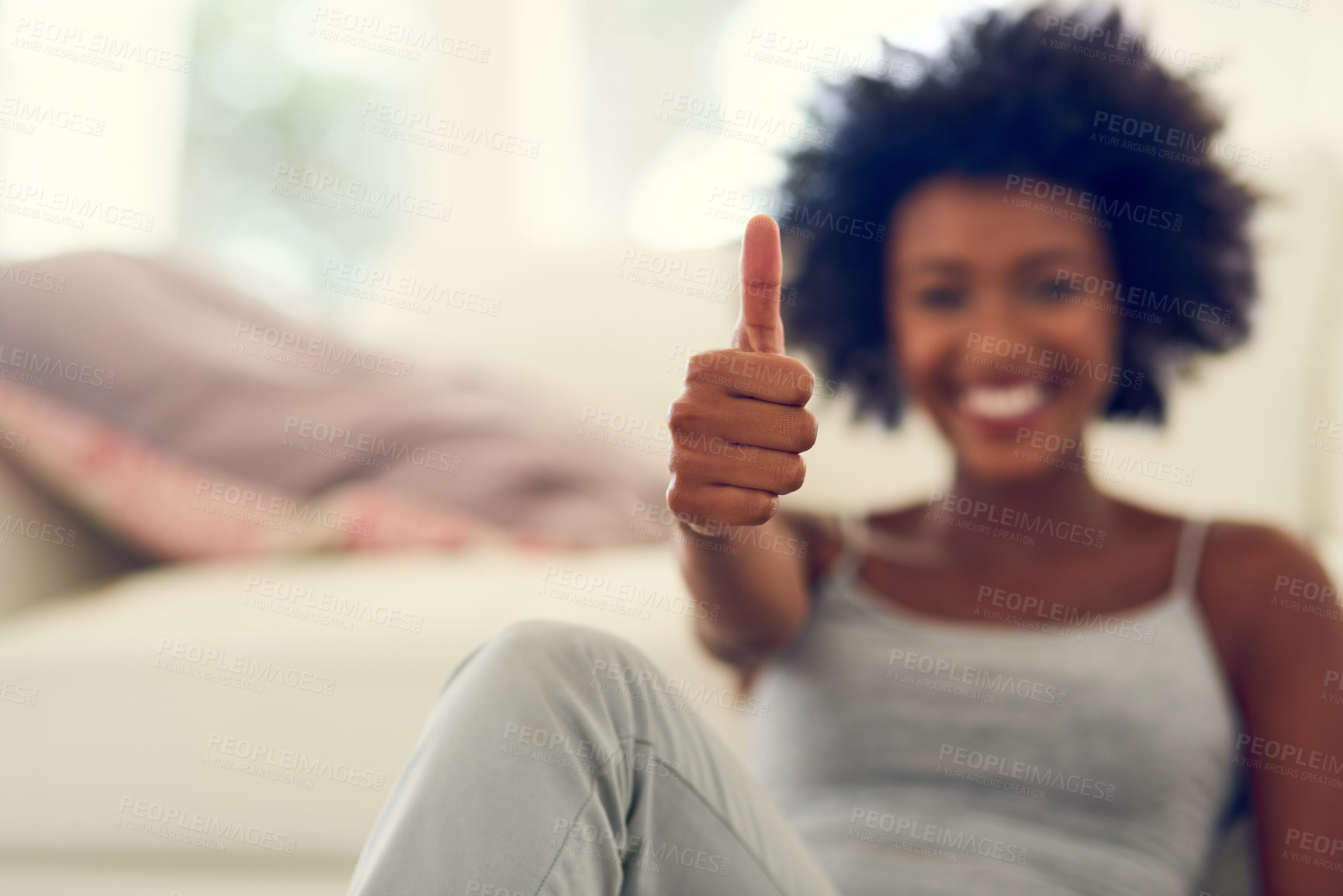 Buy stock photo Portrait of a young woman showing thumbs up while relaxing at home