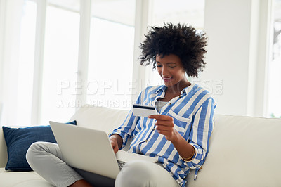Buy stock photo Cropped shot of a young woman using a credit card to make an online payment at home