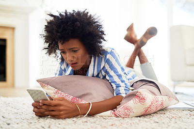 Buy stock photo Shot of a young woman texting on her cellphone at home
