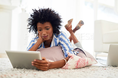 Buy stock photo Black woman, home and reading on tablet with lying on floor for social media post and news updates. Female person, living room and concentrate with streaming service or website for movies and series