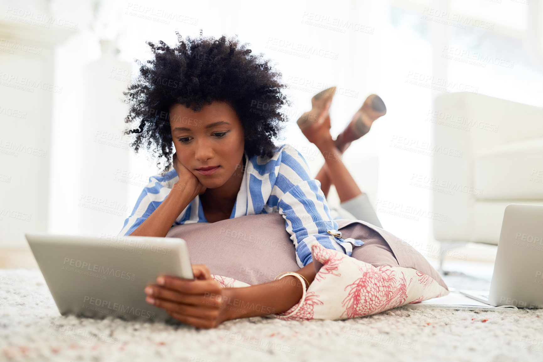 Buy stock photo Black woman, home and reading on tablet with lying on floor for social media post and news updates. Female person, living room and concentrate with streaming service or website for movies and series