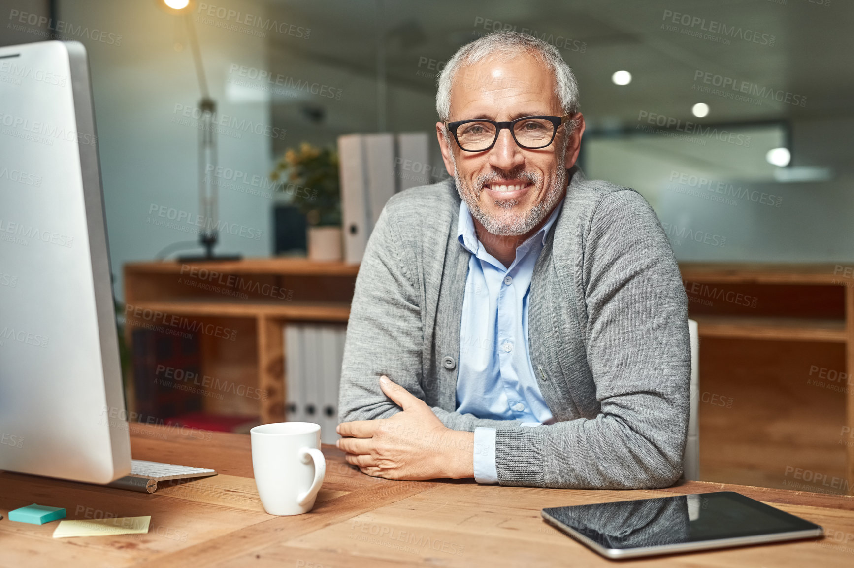 Buy stock photo Portrait of a smiling mature businessman sitting at his desk in an office