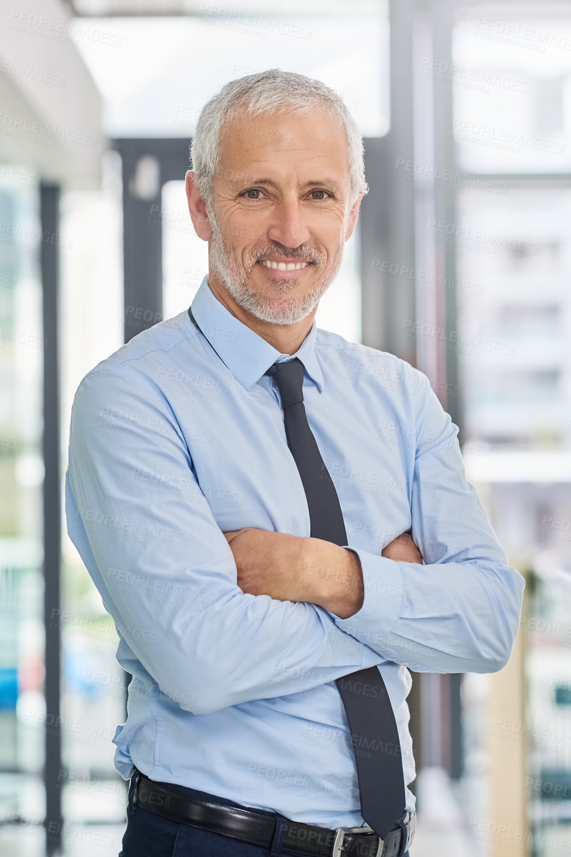 Buy stock photo Portrait of a smiling mature executive standing with his arms crossed in an office