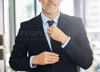 Buy stock photo Closeup shot of a mature businessman straightening his tie while standing in an office