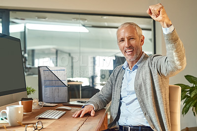 Buy stock photo Portrait of a mature businessman raisng his arm in a cheer while sitting at his desk in an office