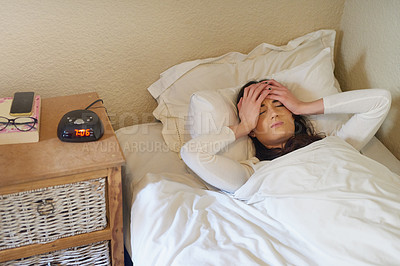 Buy stock photo Cropped shot of a young woman waking up to her alarm in the morning